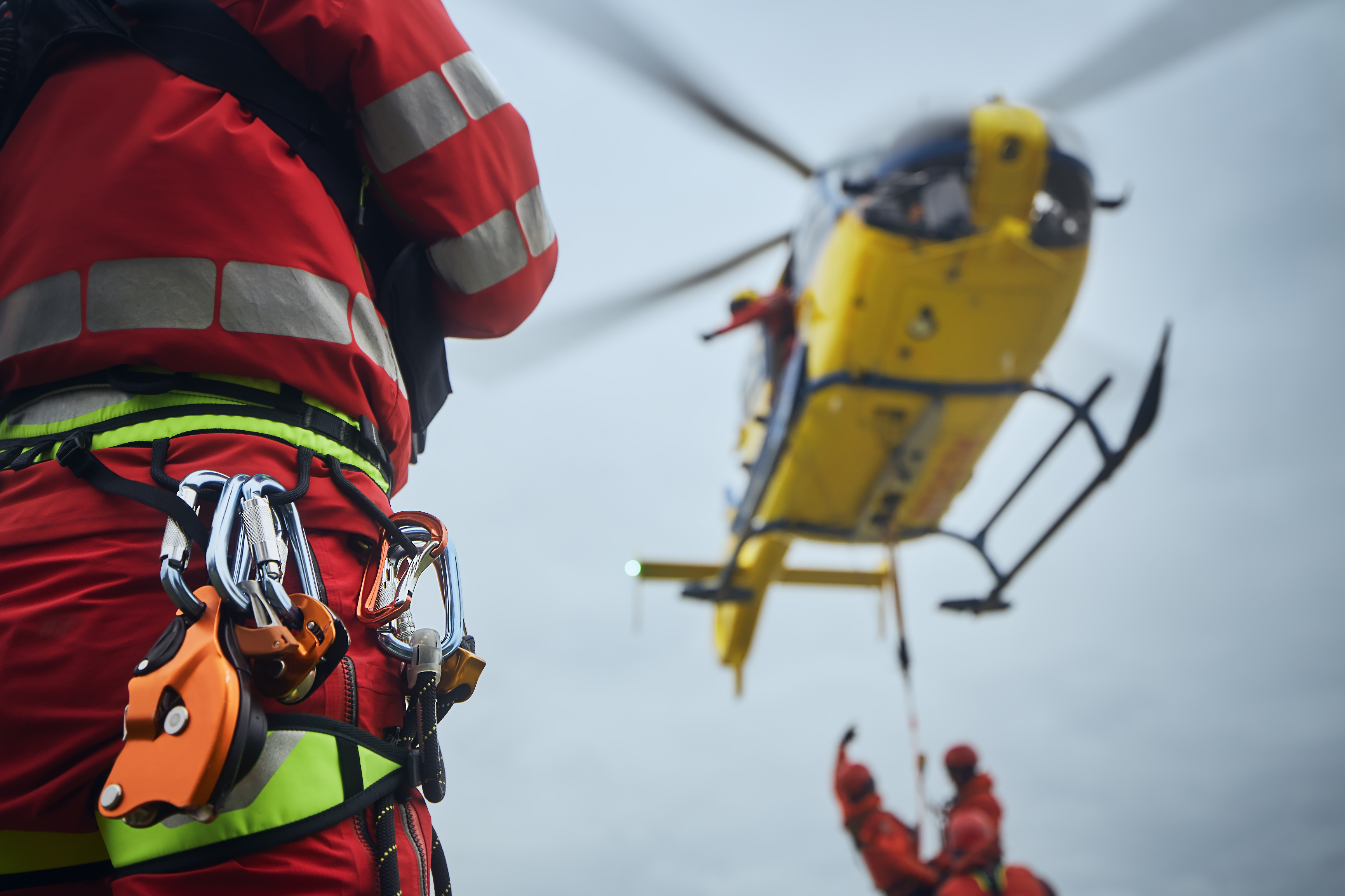Rescue responder with harness and equipment during helicopter extraction operation